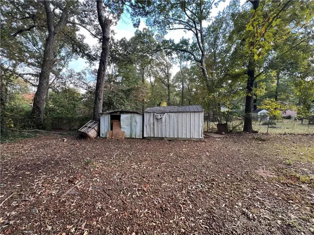 a view of a backyard with large trees and wooden fence