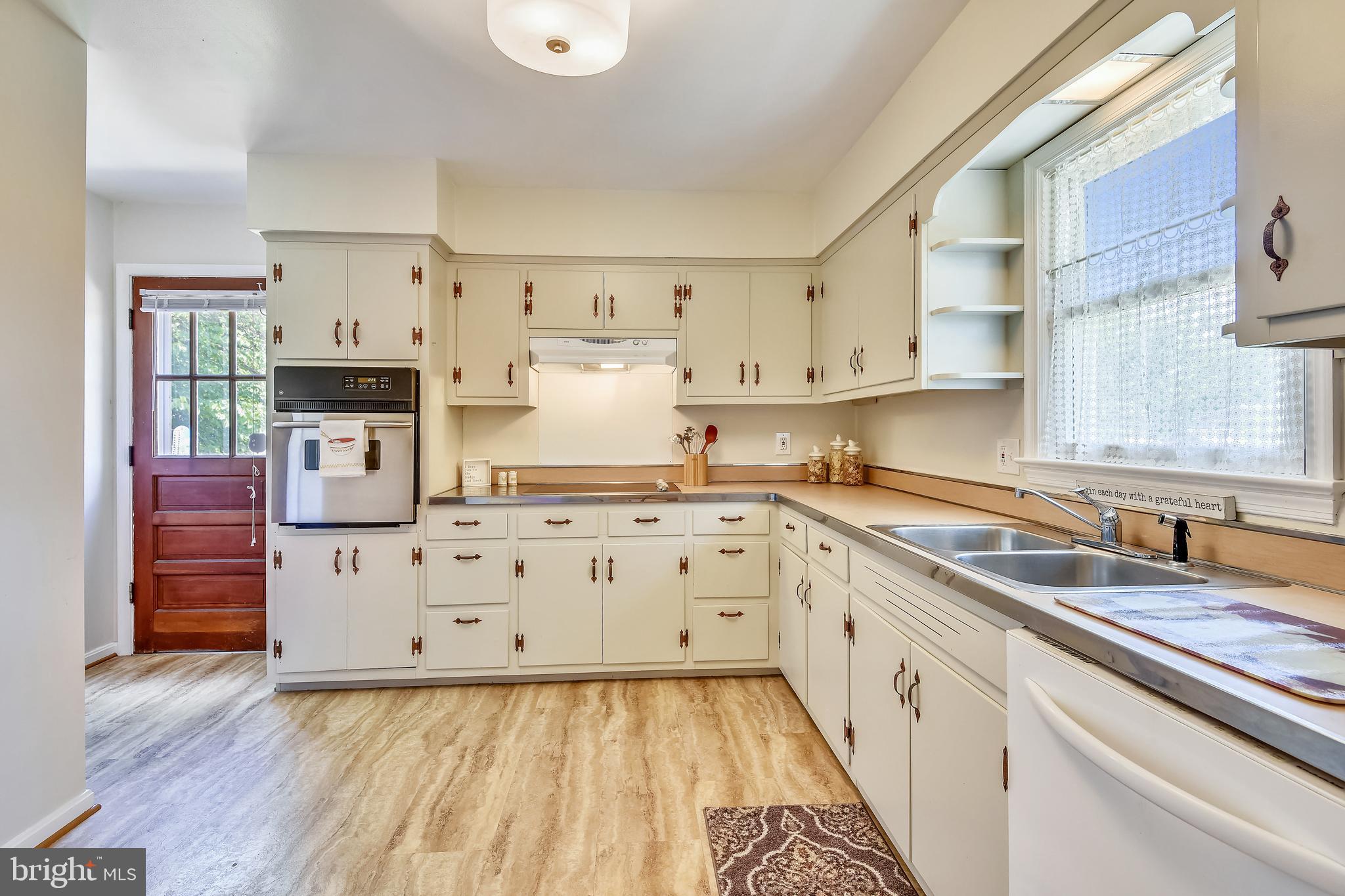 a kitchen with cabinets wooden floor and stainless steel appliances