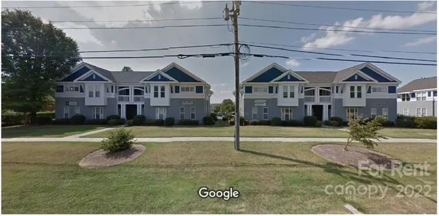 a view of a big house with a big yard and large tree