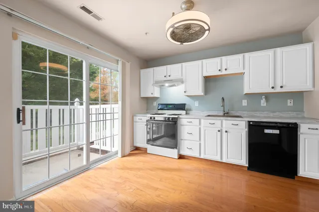 a kitchen with stainless steel appliances granite countertop a stove a sink and a granite counter tops with white cabinets