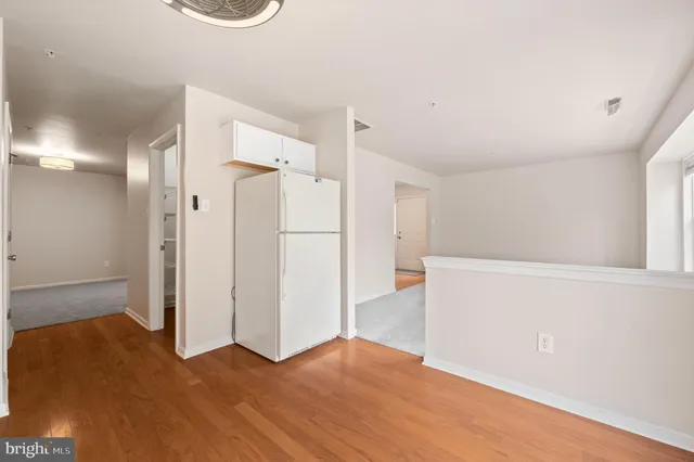 a view of an empty room with wooden floor and a bathroom