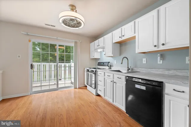 a kitchen with stainless steel appliances granite countertop a stove a sink and a granite counter tops with white cabinets