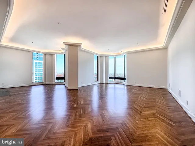 a view of an empty room with window and wooden floor