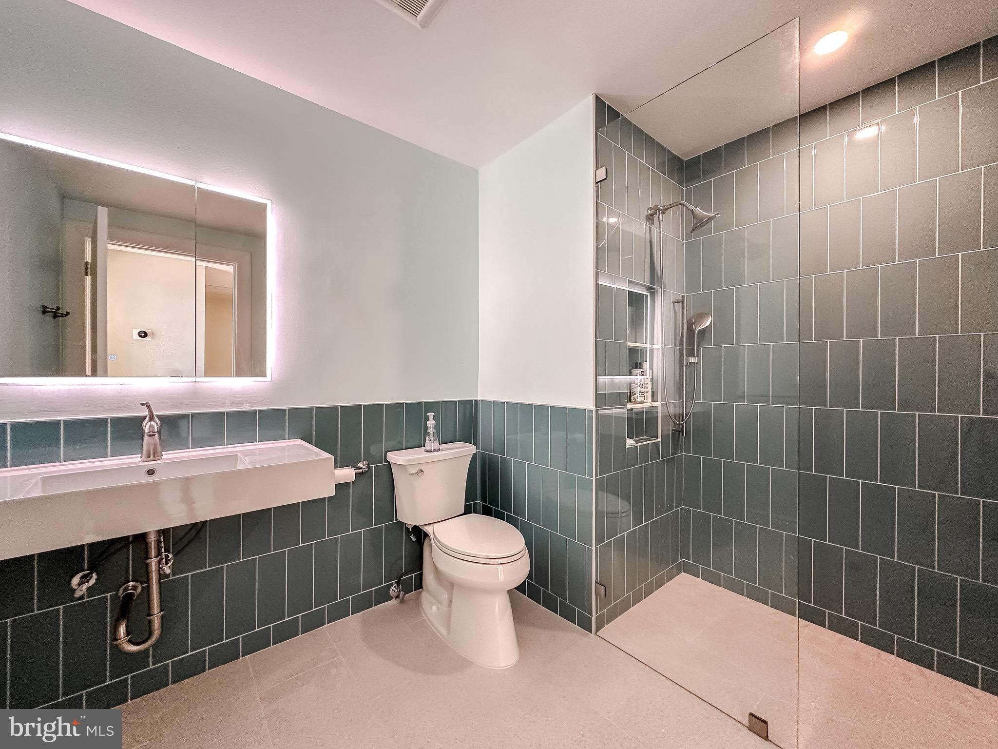 10 East Lee Street, Unit 2701 Baltimore, MD 21202 - Photo 48 of 58 a bathroom with a sink a toilet a mirror and shower