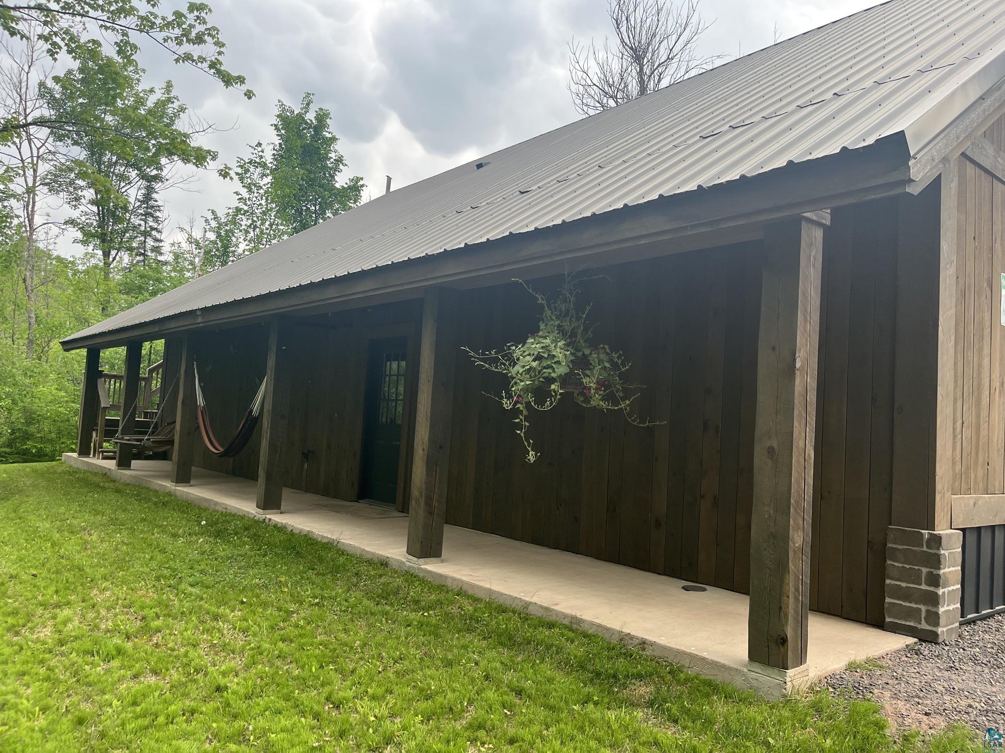 70745 Range Line Road Iron River, WI 54847 - Photo 35 of 40 Wood-sided structure featuring a covered porch, durable metal roof, and a partial brick foundation