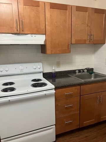 763 Main Street, Unit 44 Waltham, MA 02451 - Photo 6 of 11 a kitchen with granite countertop cabinets and a stove top oven