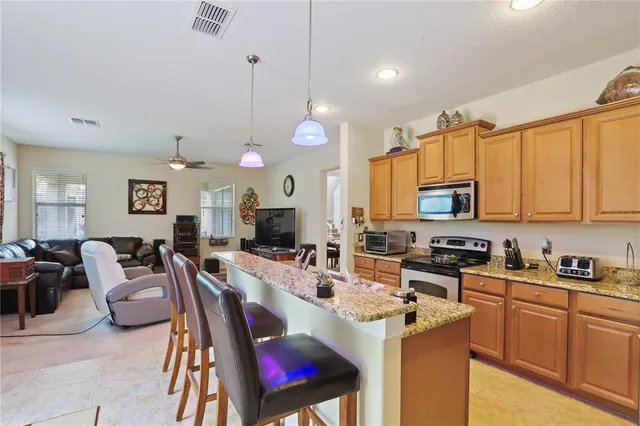 a kitchen with stainless steel appliances a stove a sink a refrigerator a center island a dining table and chairs