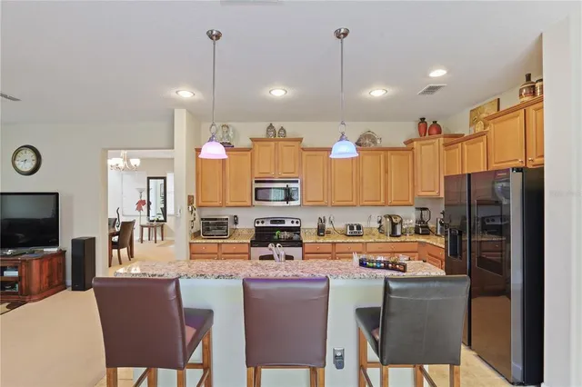 a kitchen with stainless steel appliances granite countertop a refrigerator a stove a sink dishwasher a dining table and chairs with wooden floor