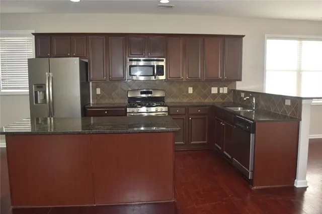 a kitchen with stainless steel appliances granite countertop a refrigerator a sink a stove a microwave a counter space and cabinets