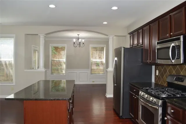 a kitchen with granite countertop stainless steel appliances a stove refrigerator a sink a stove a dining table and chairs