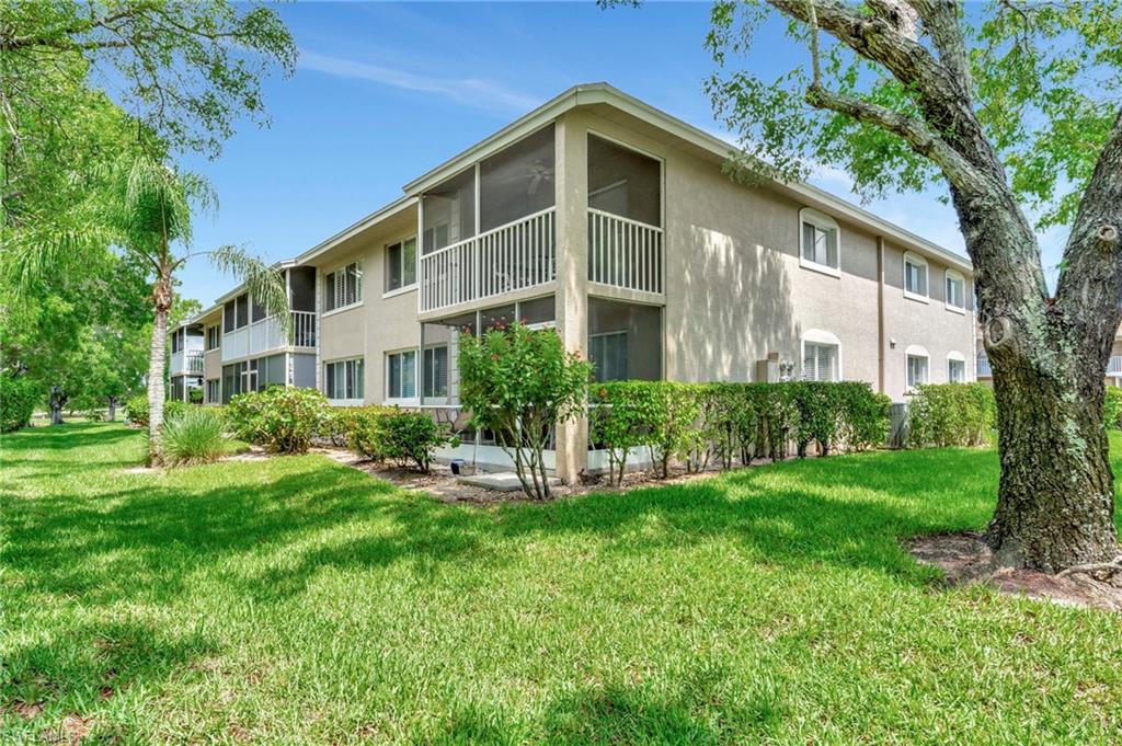 234 Pebble Beach Boulevard, Unit 305 Naples, FL 34113 - Photo 2 of 17 a front view of a house with a yard