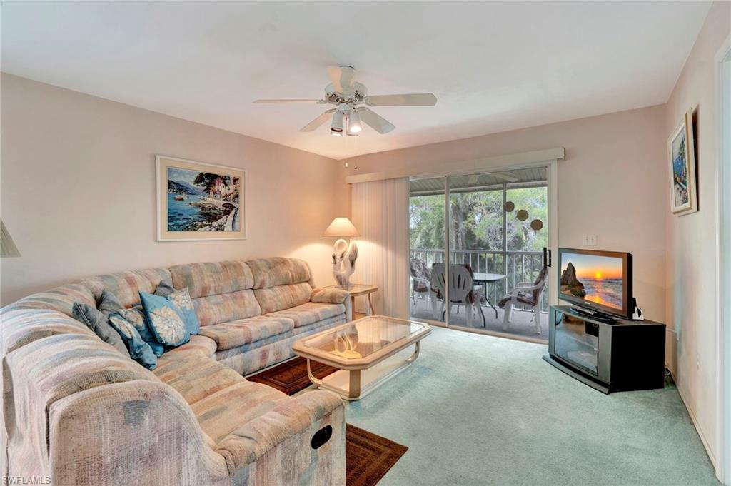 234 Pebble Beach Boulevard, Unit 305 Naples, FL 34113 - Photo 4 of 17 a living room with furniture a flat screen tv and a large window