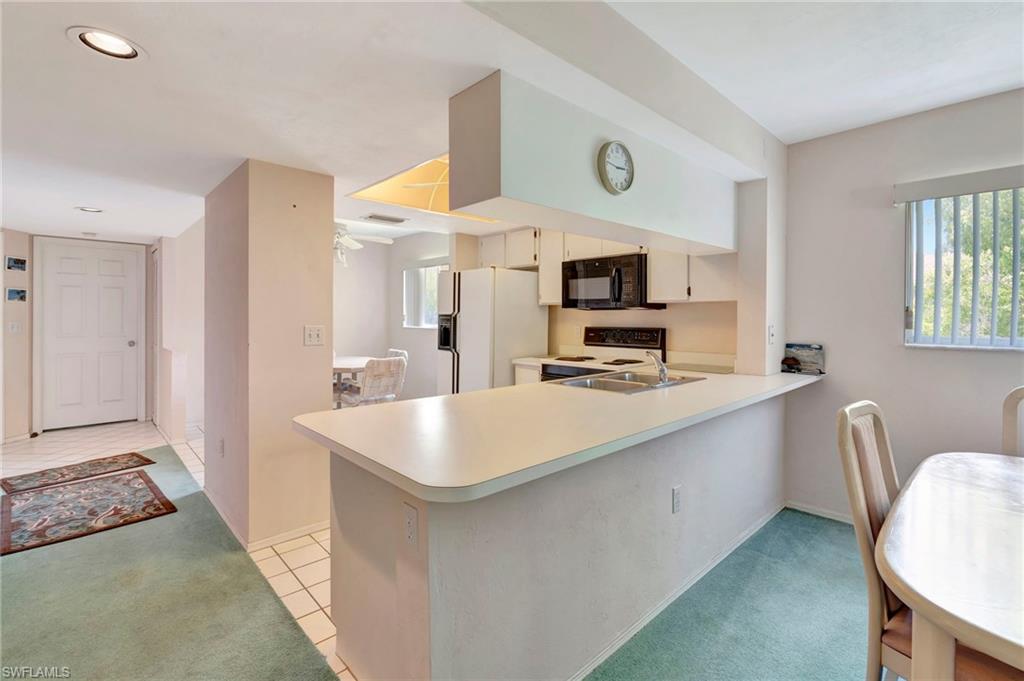 234 Pebble Beach Boulevard, Unit 305 Naples, FL 34113 - Photo 9 of 17 a large white kitchen with a sink a microwave and refrigerator