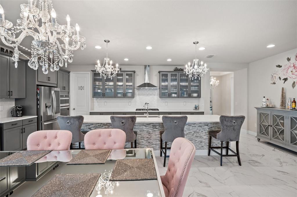 5632 Long Shore Loop Sarasota, FL 34238 - Photo 24 of 56 a kitchen with stainless steel appliances kitchen island granite countertop a dining table chairs and chandelier