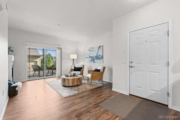 a kitchen with stainless steel appliances granite countertop a stove top oven a refrigerator a dining table and chairs with wooden floor