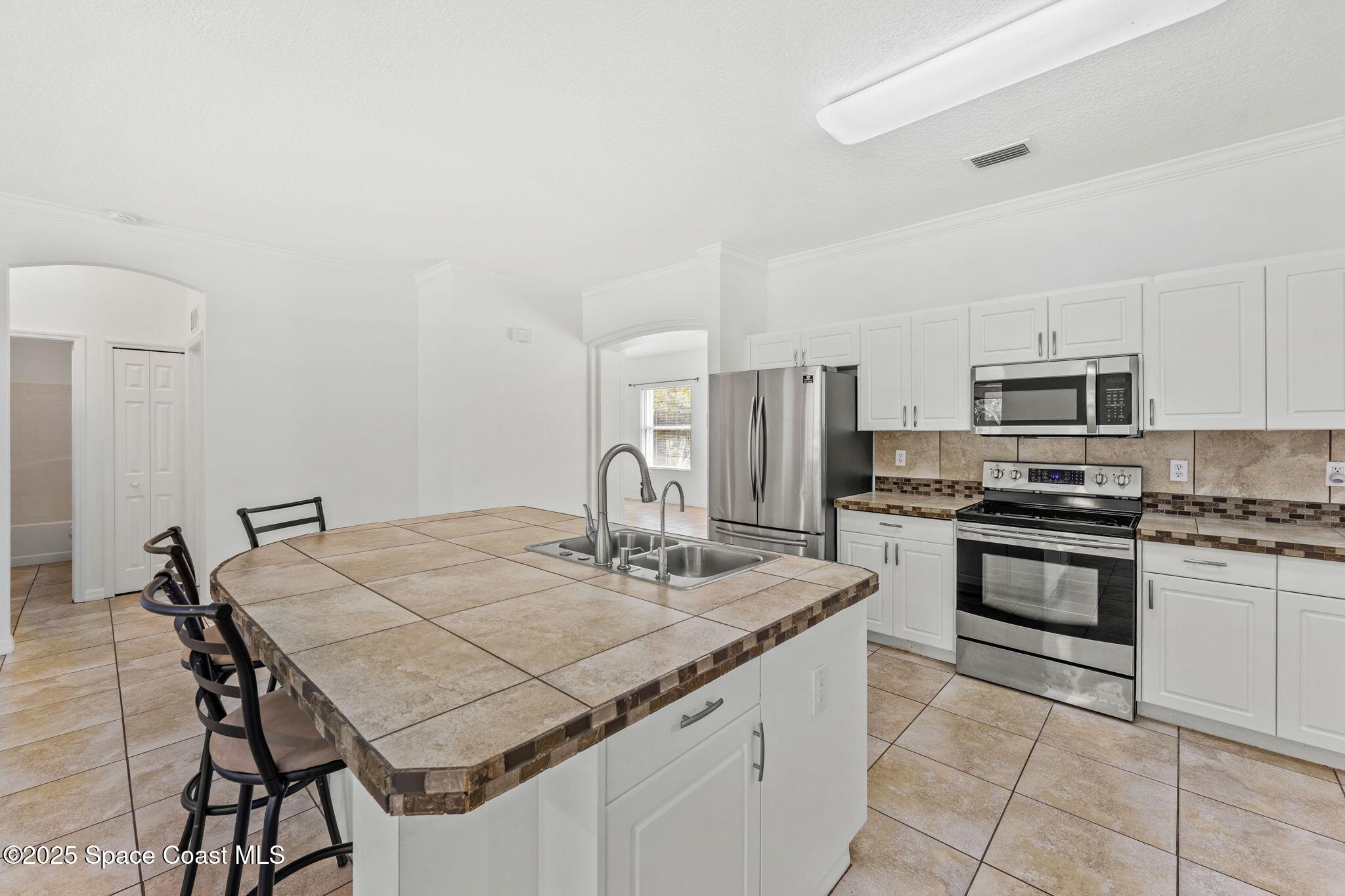 1385 Friday Road Cocoa, FL 32926 - Photo 9 of 33 a kitchen with stainless steel appliances granite countertop a kitchen island a stove a table and chairs