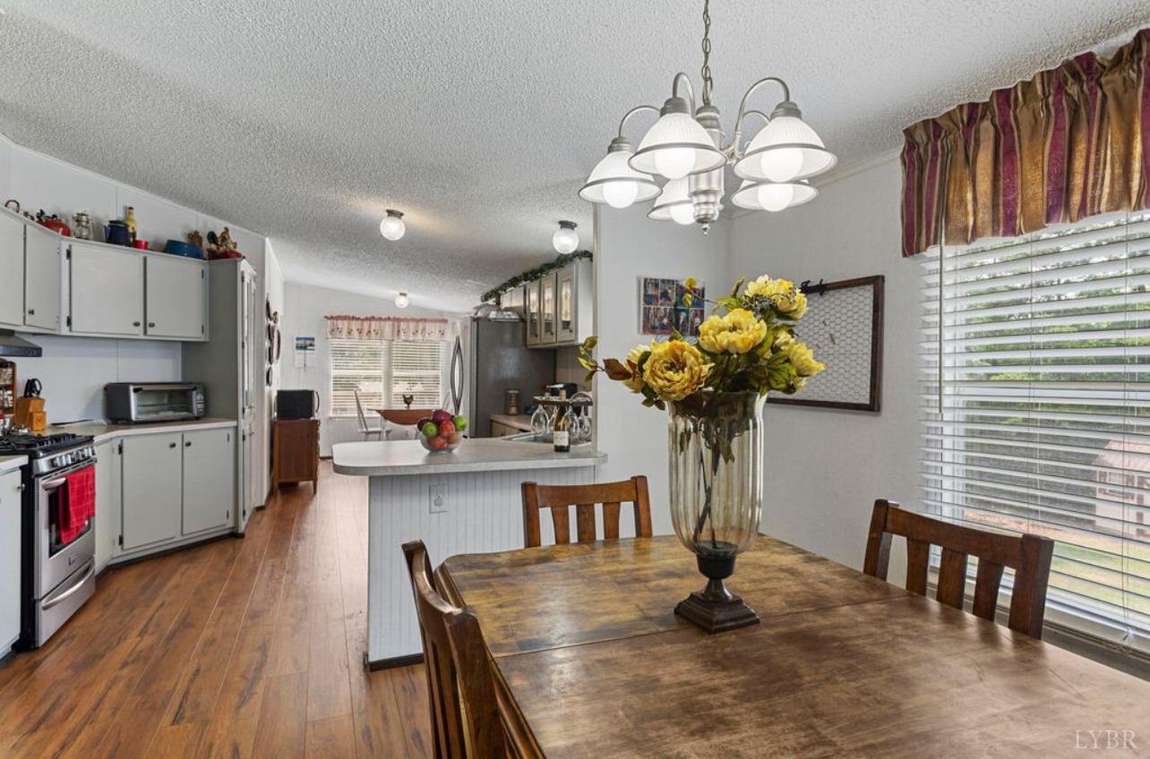 1362 Peaceful Ridge Road Huddleston, VA 24104 - Photo 8 of 19 a kitchen with stainless steel appliances granite countertop a refrigerator a sink dishwasher a dining table and chairs with wooden floor