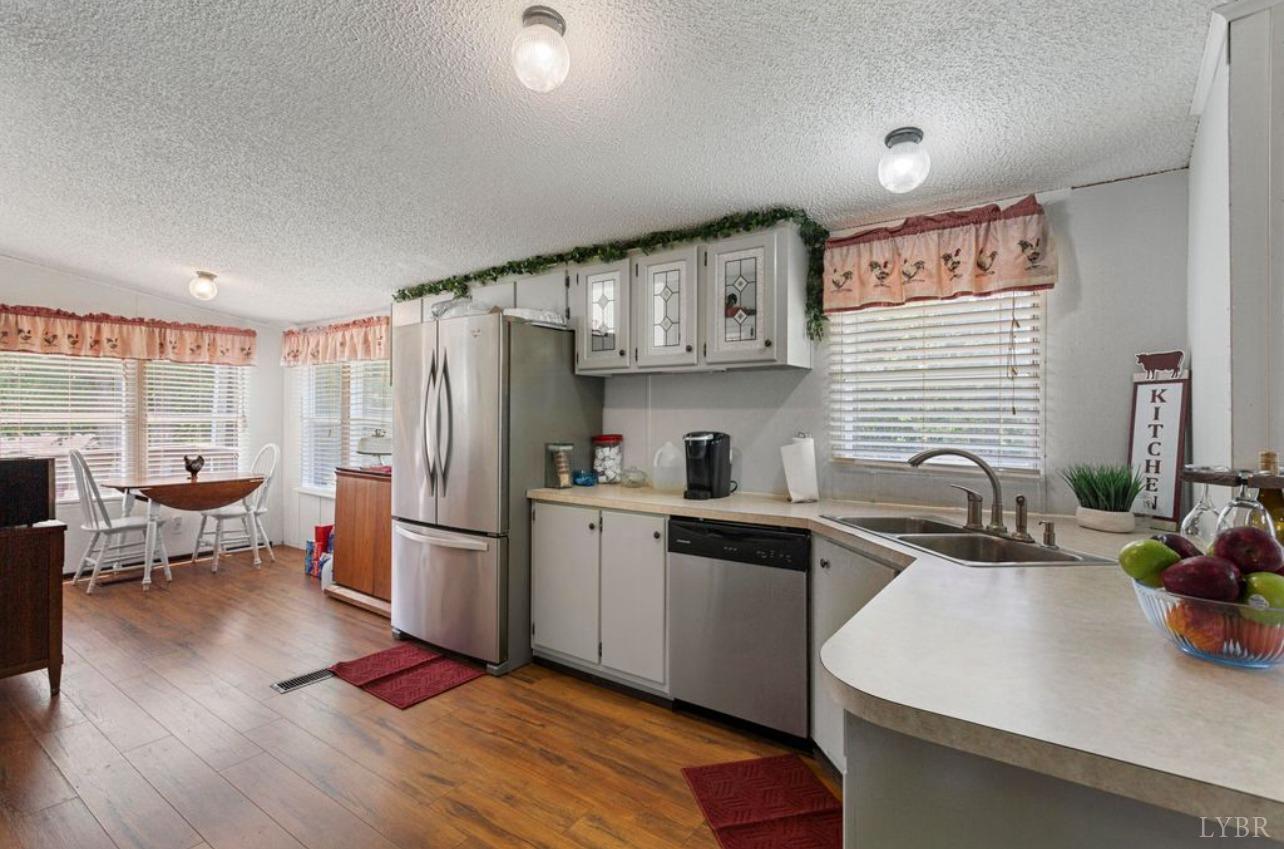 1362 Peaceful Ridge Road Huddleston, VA 24104 - Photo 10 of 19 a kitchen with stainless steel appliances granite countertop a sink dishwasher a refrigerator a stove and white cabinets with wooden floor