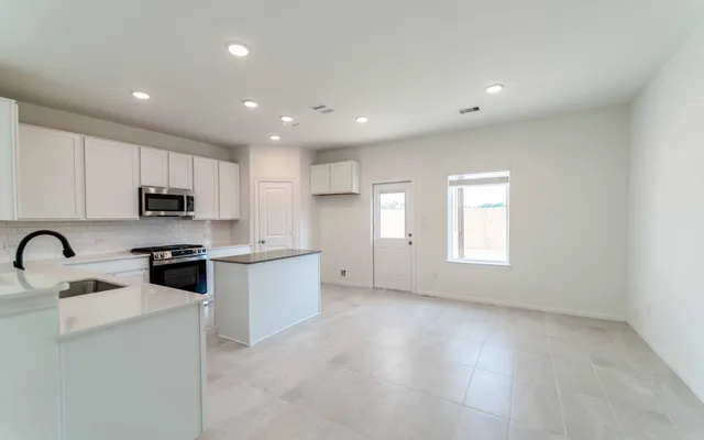 a kitchen with granite countertop white cabinets stainless steel appliances and a window