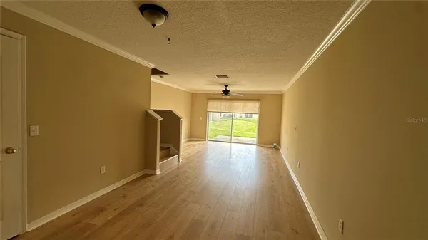 a view of empty room with wooden floor and fan