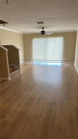 an empty room with wooden floor cabinet and windows