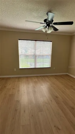 an empty room with wooden floor fan and windows