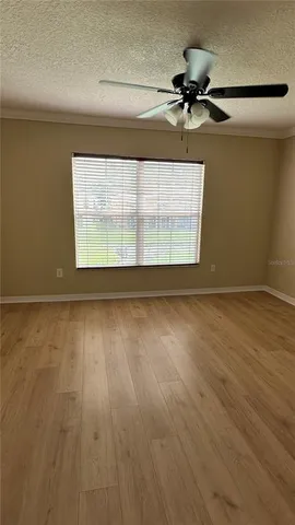 an empty room with wooden floor fan and windows