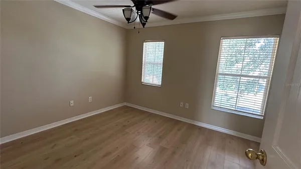 a view of an empty room with a window and wooden floor