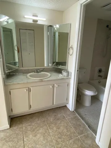 a bathroom with a granite countertop sink toilet and mirror