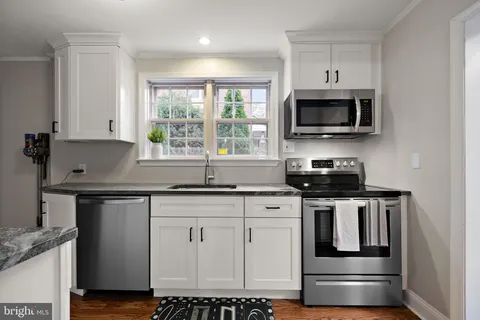 a kitchen with stainless steel appliances granite countertop a sink a stove and a microwave