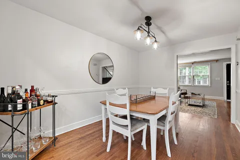 a dining room with wooden floor a chandelier a wooden table and chairs