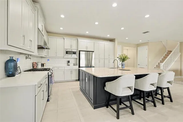 a kitchen with stainless steel appliances kitchen island granite countertop a table chairs sink and cabinets