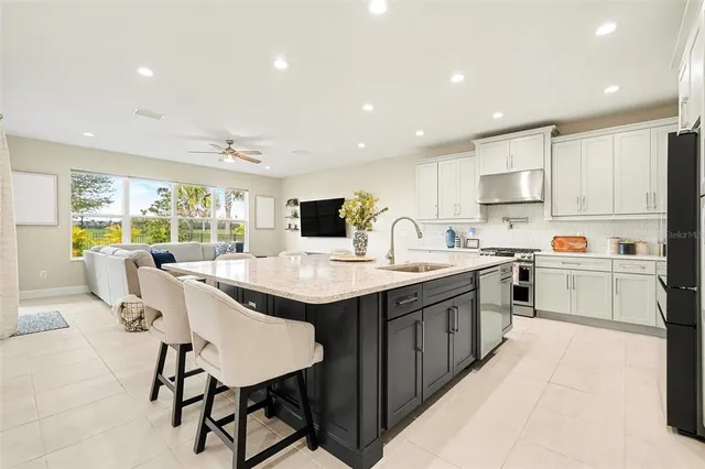 a kitchen with stainless steel appliances kitchen island granite countertop a table chairs sink and cabinets