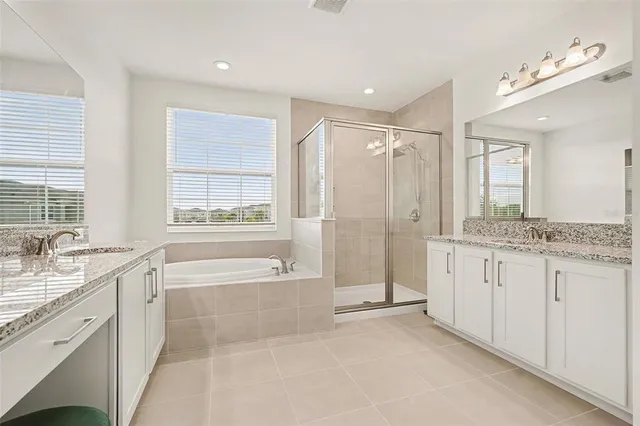 a spacious bathroom with a granite countertop tub sink shower and mirror