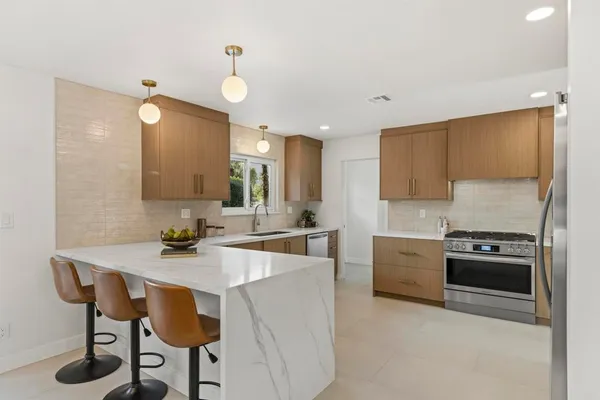 a kitchen with kitchen island a stove a table and chairs in it