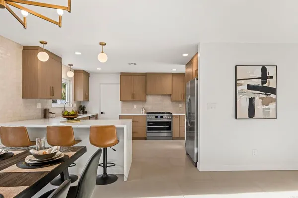 a kitchen with kitchen island granite countertop a stove top oven a sink a dining table and chairs with wooden floor