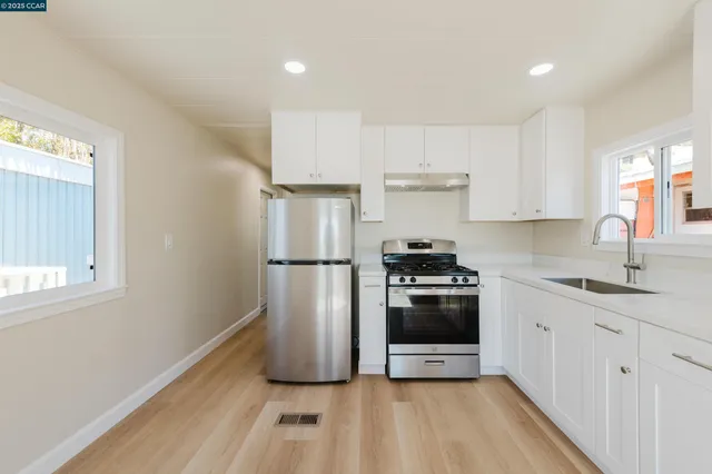 a kitchen with stainless steel appliances a refrigerator sink and white cabinets