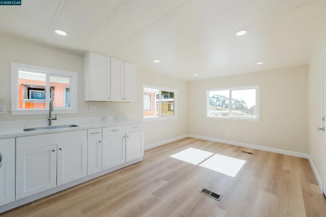 a view of a kitchen with dishwasher and white cabinets with wooden floor