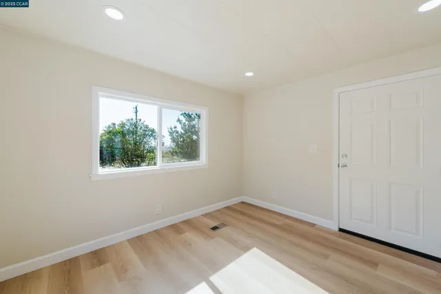 an empty room with wooden floor and window