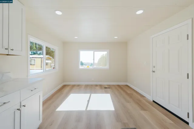 an empty room with wooden floor and windows