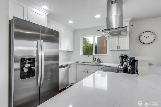 a kitchen with stainless steel appliances a dining table chairs refrigerator and cabinets