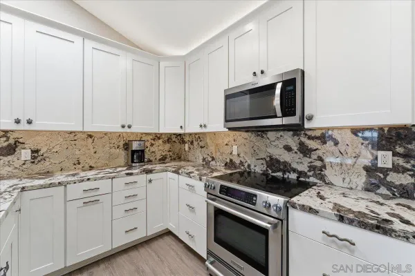 a kitchen with granite countertop a sink stove and cabinets