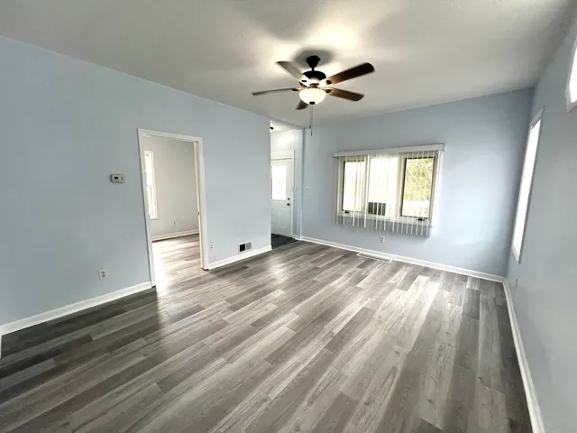 a view of empty room with wooden floor and fan