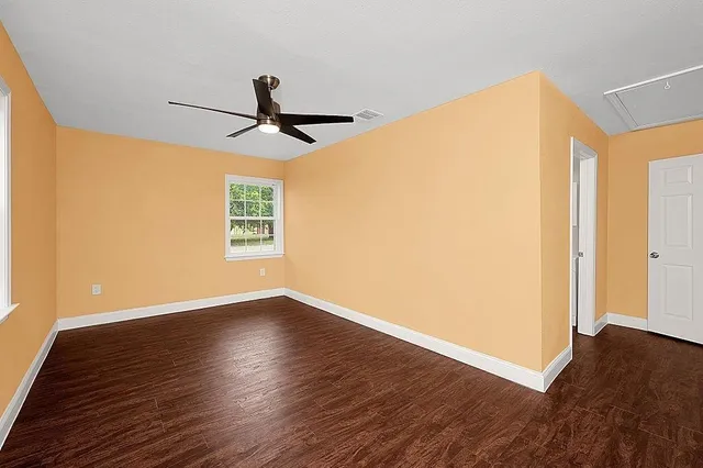 a view of empty room with wooden floor and fan