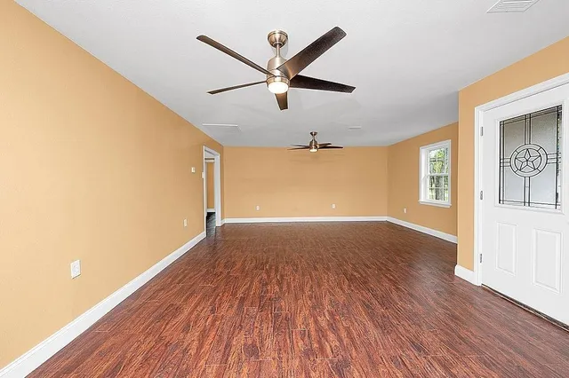 a view of a big room with wooden floor and windows