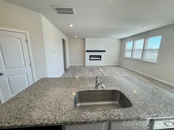 a kitchen with granite countertop white cabinets stainless steel appliances and a counter space