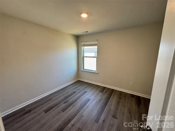 a view of an empty room with wooden floor and closet