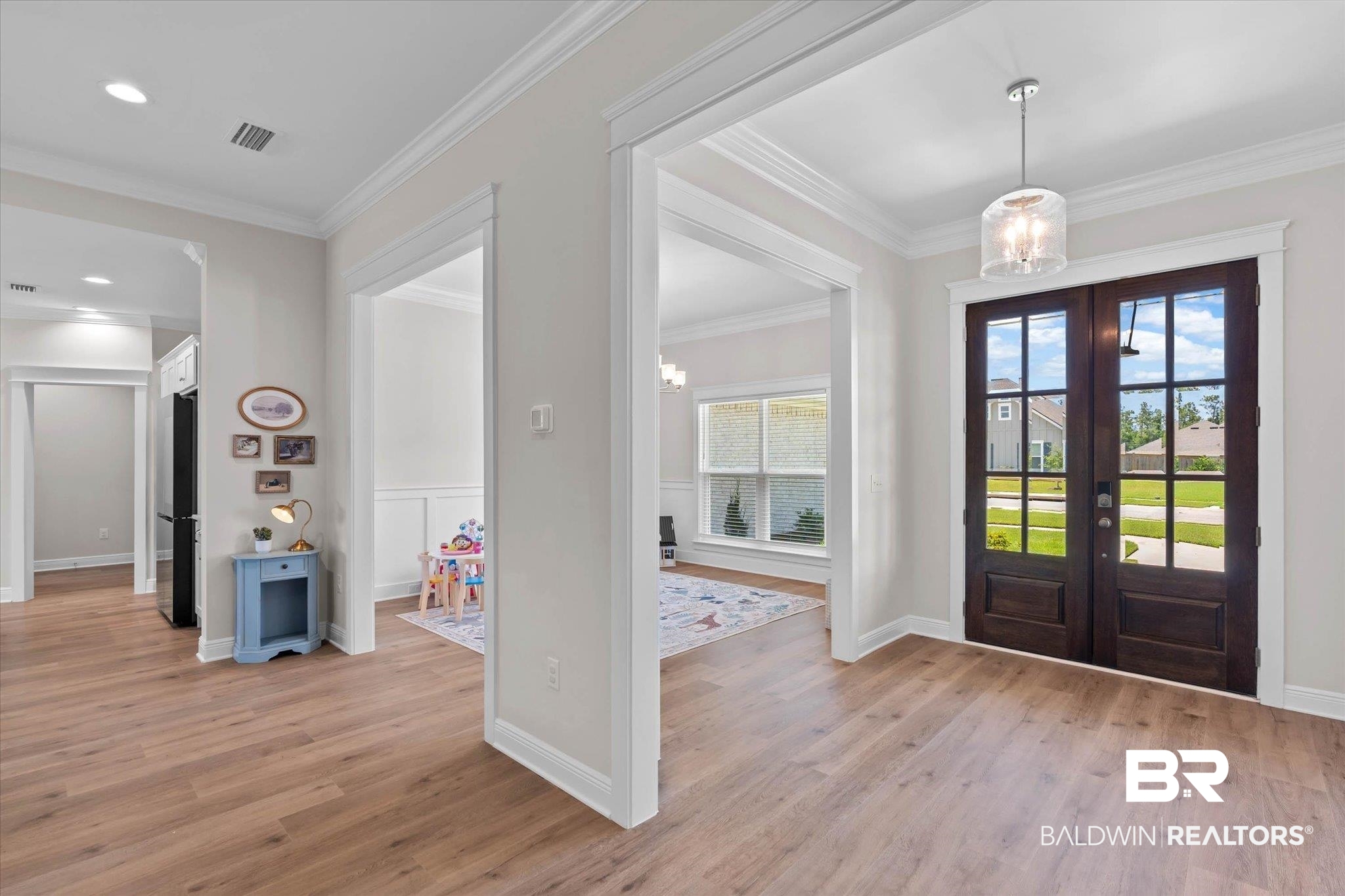 23523 Travis Stock Street Foley, AL 36535 - Photo 3 of 45 Light wood-finish flooring throughout, featuring a double-door entry with glass panels, a drum pendant light fixture, and wide entryway archways