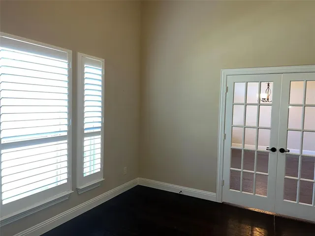 an empty room with wooden floor fireplace and windows