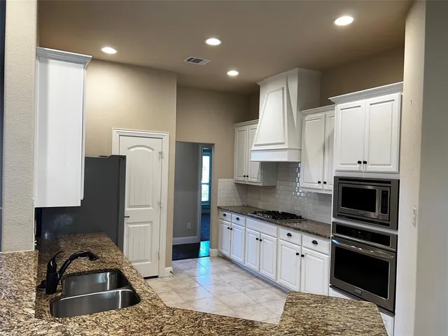 a kitchen with stainless steel appliances granite countertop a stove a sink and a refrigerator